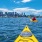 a person in a kayak in the water with a city in the background